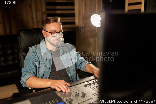 Image of man at mixing console in music recording studio