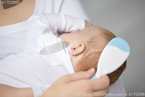 Image of close up of mother brushing newborn baby hair