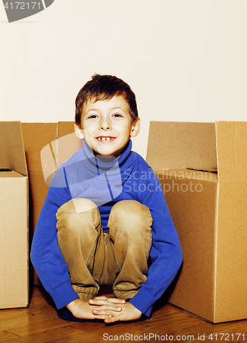 Image of little cute boy in empty room, remoove to new house. home alone emong boxes close up kid