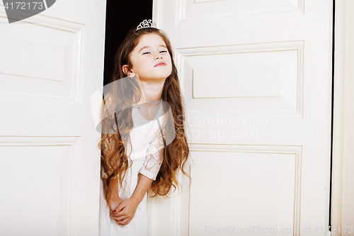 Image of little cute girl at home, opening door well-dressed in white dre