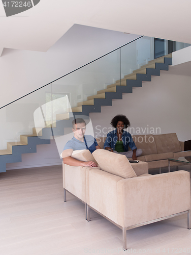 Image of young multiethnic couple relaxes in the living room