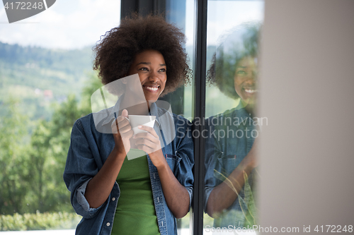 Image of African American woman drinking coffee looking out the window