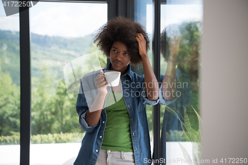 Image of African American woman drinking coffee looking out the window