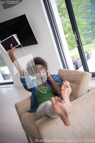 Image of African american woman at home in chair with tablet and head pho