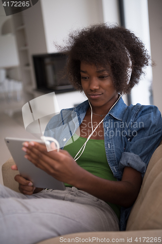 Image of African american woman at home in chair with tablet and head pho