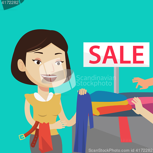 Image of Young woman choosing clothes in shop on sale.