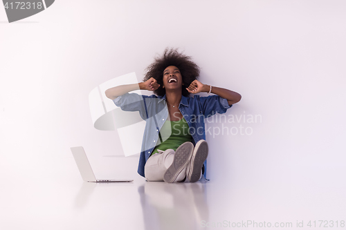 Image of african american woman sitting on floor with laptop