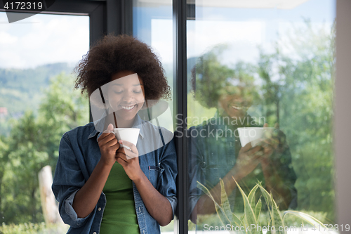 Image of African American woman drinking coffee looking out the window