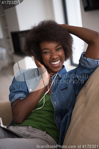 Image of African american woman at home in chair with tablet and head pho