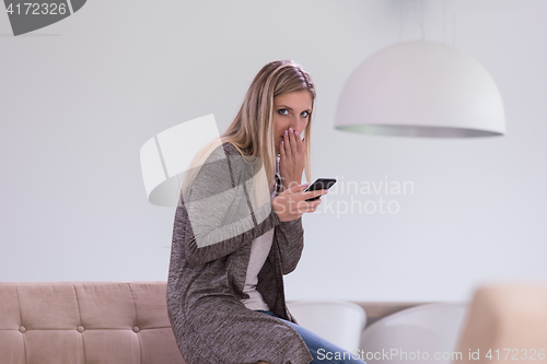 Image of woman sitting on sofa with mobile phone