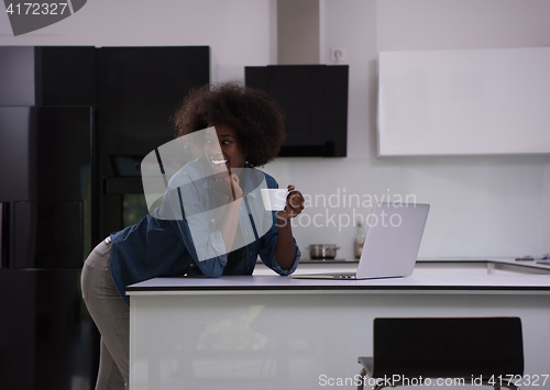 Image of smiling black woman in modern kitchen