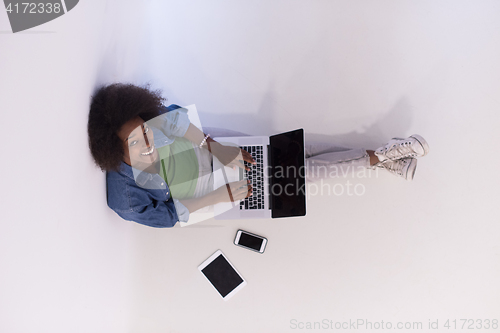 Image of african american woman sitting on floor with laptop top view