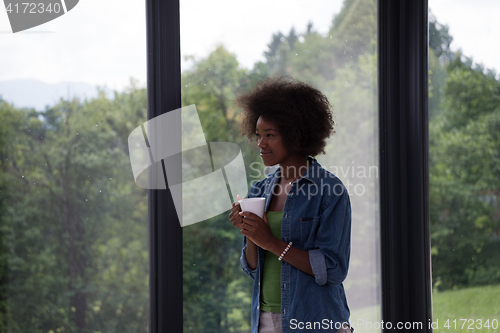 Image of African American woman drinking coffee looking out the window