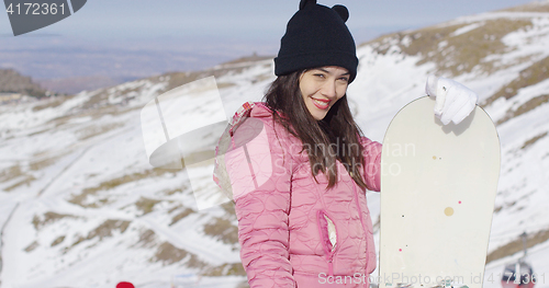 Image of Smiling woman with snowboard in mountains