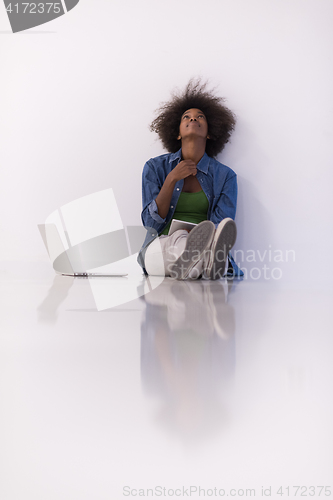 Image of african american woman sitting on floor with laptop