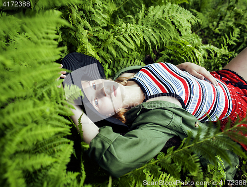 Image of Pretty young blond girl hipster in hat among fern, vacation in green forest 