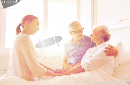 Image of happy family visiting senior woman at hospital