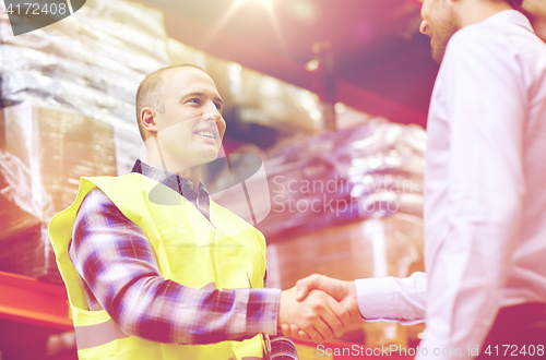 Image of worker and businessmen with clipboard at warehouse