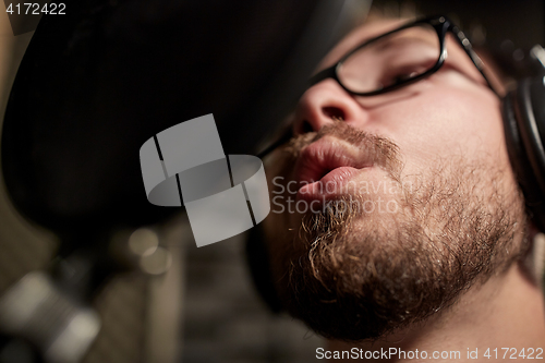 Image of man with headphones singing at recording studio