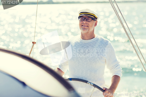 Image of senior man at helm on boat or yacht sailing in sea