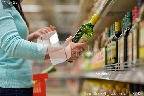 Image of woman buying olive oil at supermarket or grocery