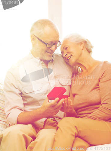 Image of happy senior couple with red gift box at home