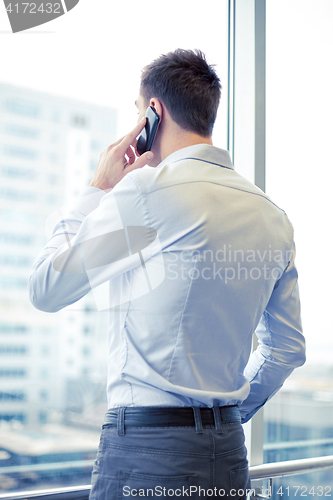 Image of businessman calling on smartphone in office