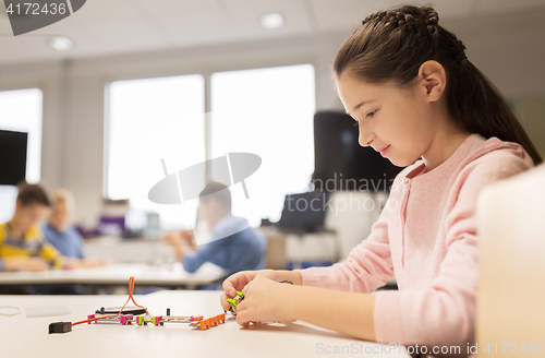 Image of happy girl building robot at robotics school