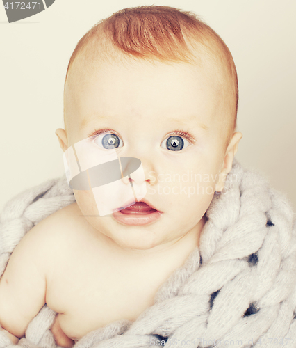 Image of little cute red head baby in scarf all over him close up isolate