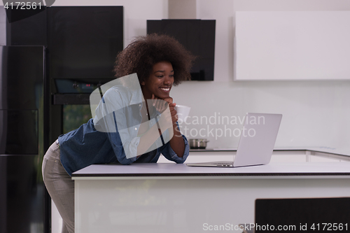 Image of smiling black woman in modern kitchen