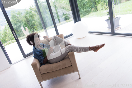 Image of African american woman at home in chair with tablet and head pho