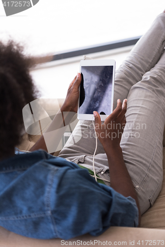 Image of African american woman at home in chair with tablet and head pho