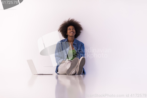 Image of african american woman sitting on floor with laptop