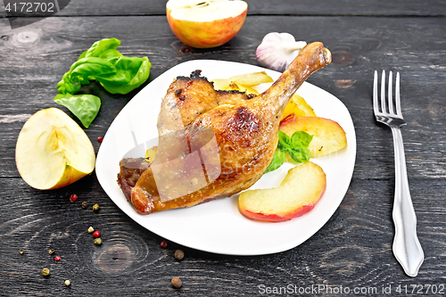 Image of Duck leg with apple and basil on black board