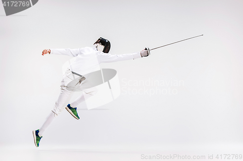 Image of Man wearing fencing suit practicing with sword against gray