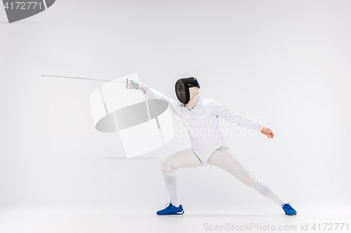 Image of Man wearing fencing suit practicing with sword against gray