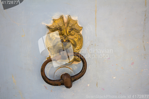 Image of Old rusty metal door knocker on an old wooden entrance door