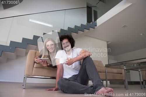 Image of couple relaxing at  home with tablet computers