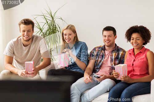 Image of happy friends with popcorn watching tv at home