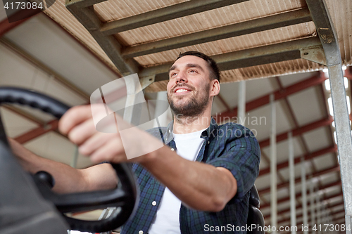 Image of man or farmer driving tractor at farm