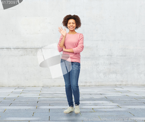 Image of happy african american young woman waving hand