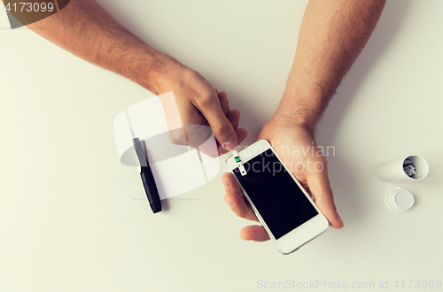 Image of close up of man with smartphone making blood test