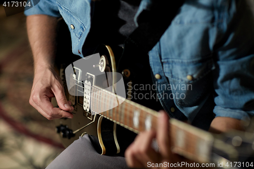 Image of close up of man playing guitar at studio rehearsal