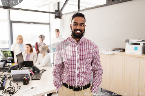 Image of happy indian man over creative team in office