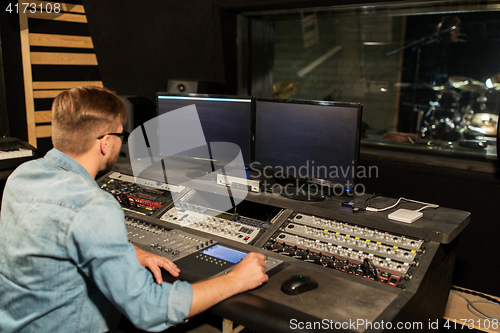 Image of man at mixing console in music recording studio