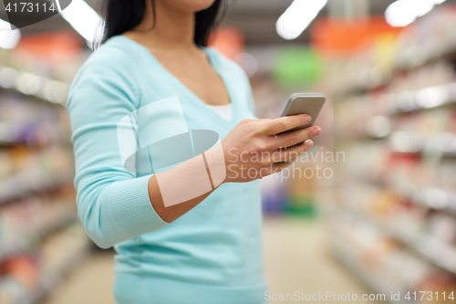 Image of woman with smartphone at shop or supermarket