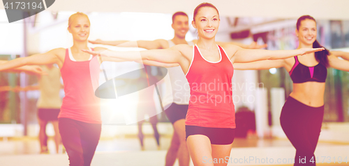 Image of group of smiling people exercising in the gym