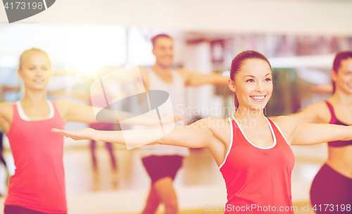 Image of group of smiling people exercising in the gym