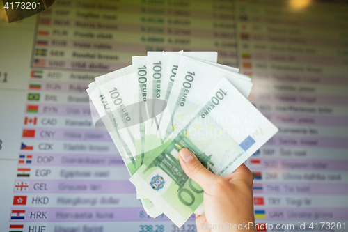 Image of hand with euro money over currency exchange rates