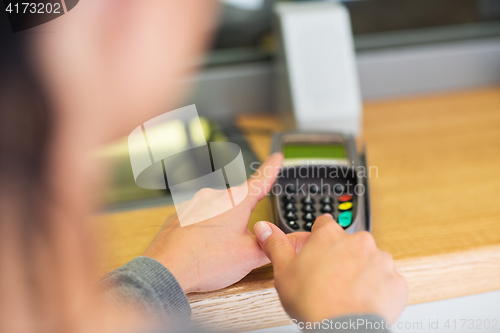 Image of hand entering pin code to card reader terminal